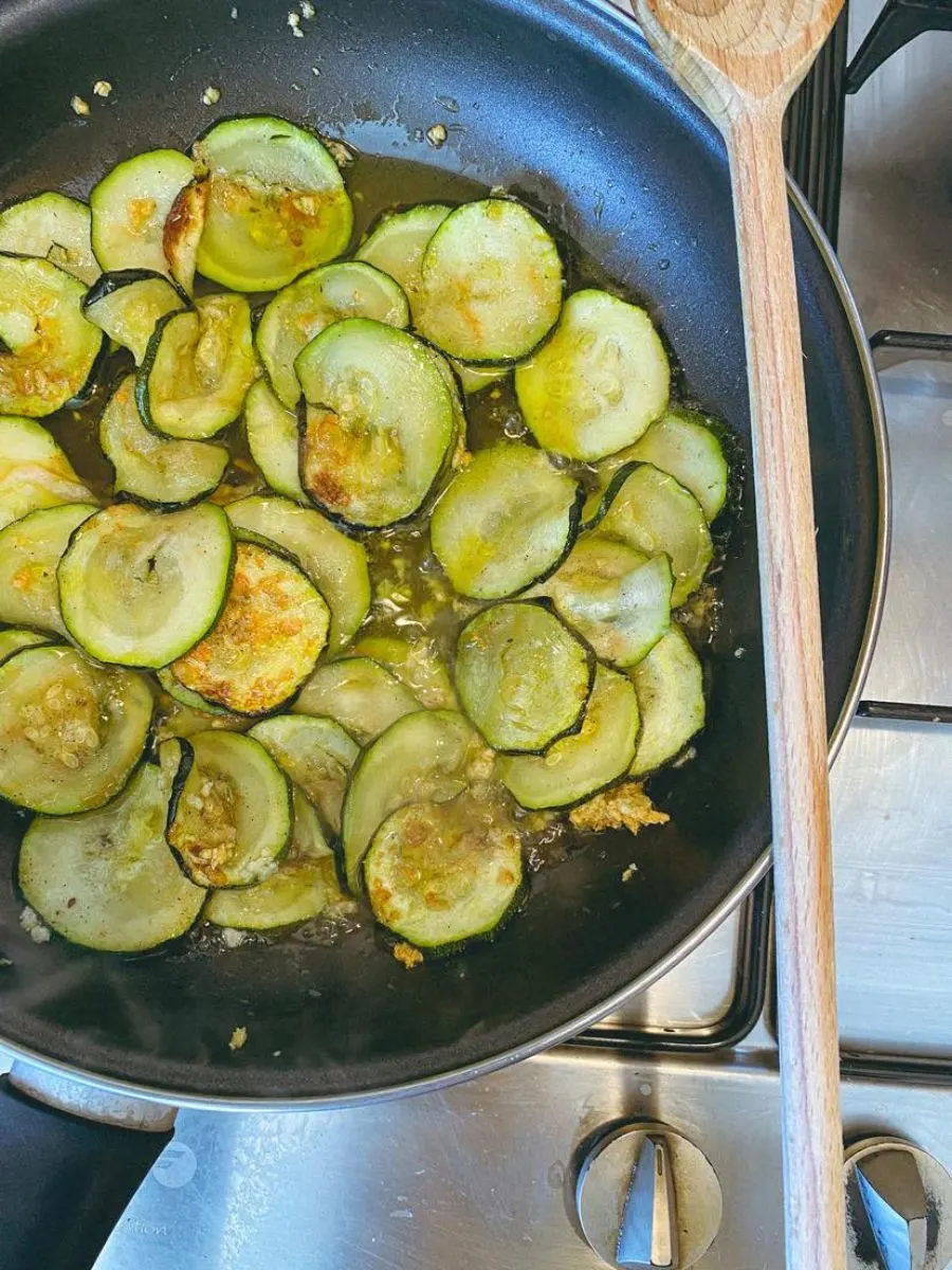sliced zucchini in a pan with garlic and pasta water
