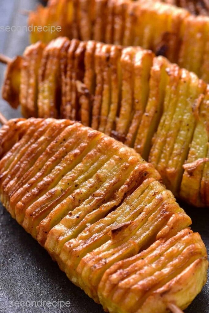 Crispy hasselback potatoes on skewers, close-up shot.