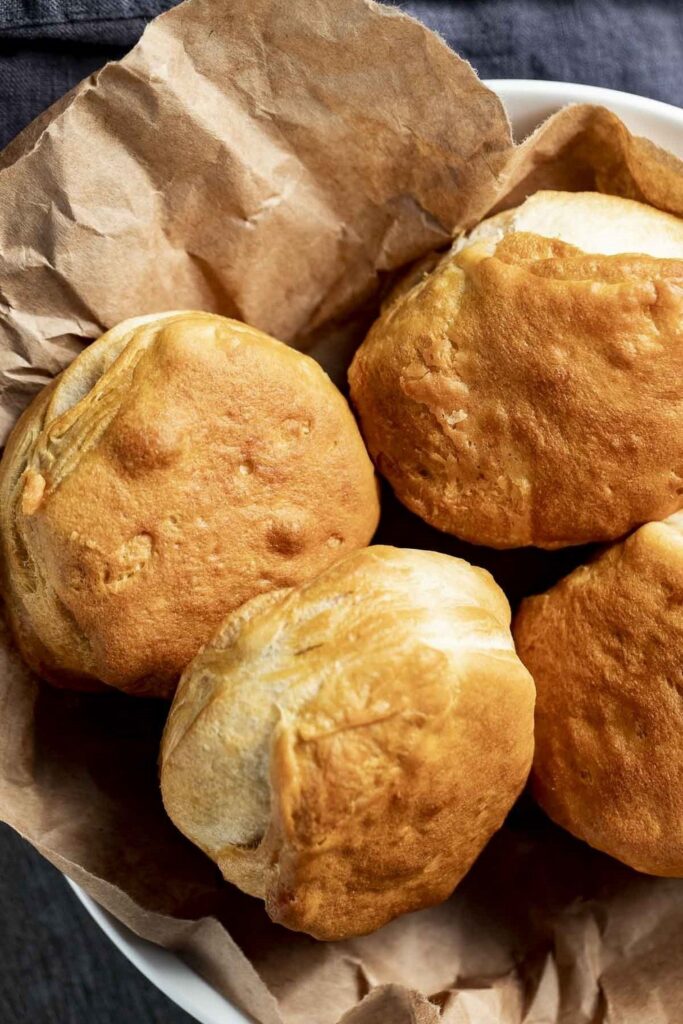 Freshly baked bread rolls in a paper-lined bowl, golden brown and ready to eat.