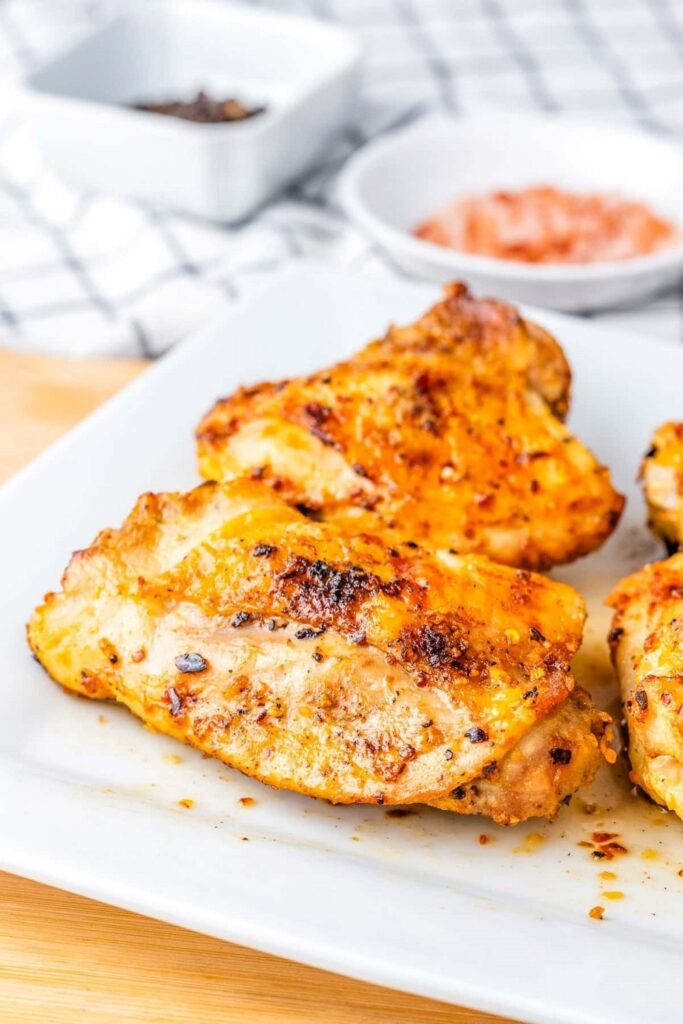 Juicy, seasoned chicken thighs on a white plate, ready to eat.