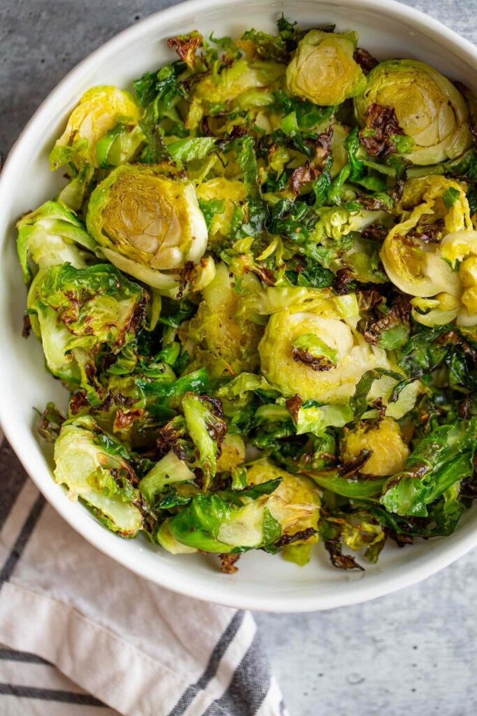 Bowl of crispy roasted Brussels sprouts with golden-brown leaves, healthy side dish.