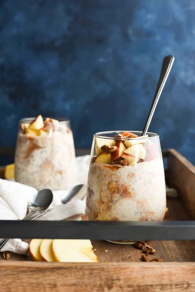 Apple Butter Overnight Oats Two glasses of apple cinnamon overnight oats, garnished with apples and nuts, on a wooden tray. Overnight Oats Recipes.