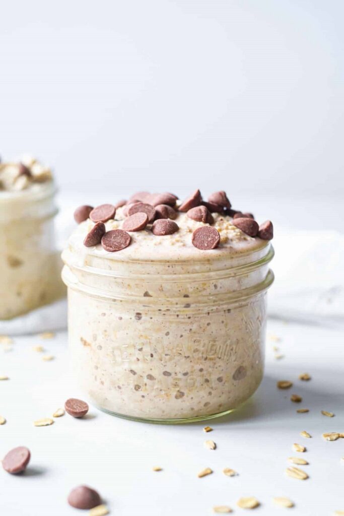 Cookie Dough Overnight Oats Jar of chocolate chip overnight oats recipe, with oats scattered around.