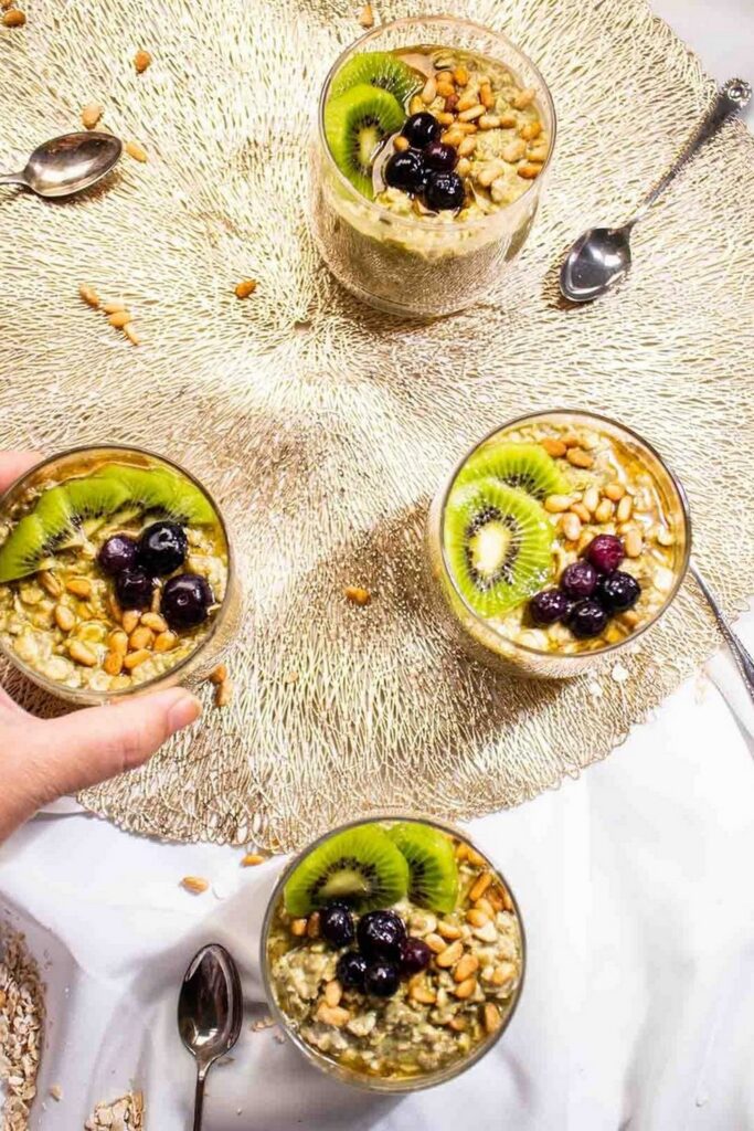 Matcha Overnight Oats Df Overnight oats recipes: Four glass cups filled with overnight oats, topped with kiwi, blueberries, and nuts.