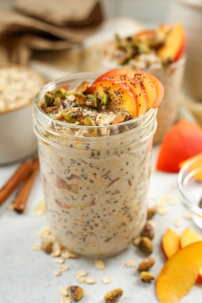 Overnight Oats Peaches Cream Jar of peach overnight oats topped with pistachios and chia seeds. Healthy overnight oats recipe.