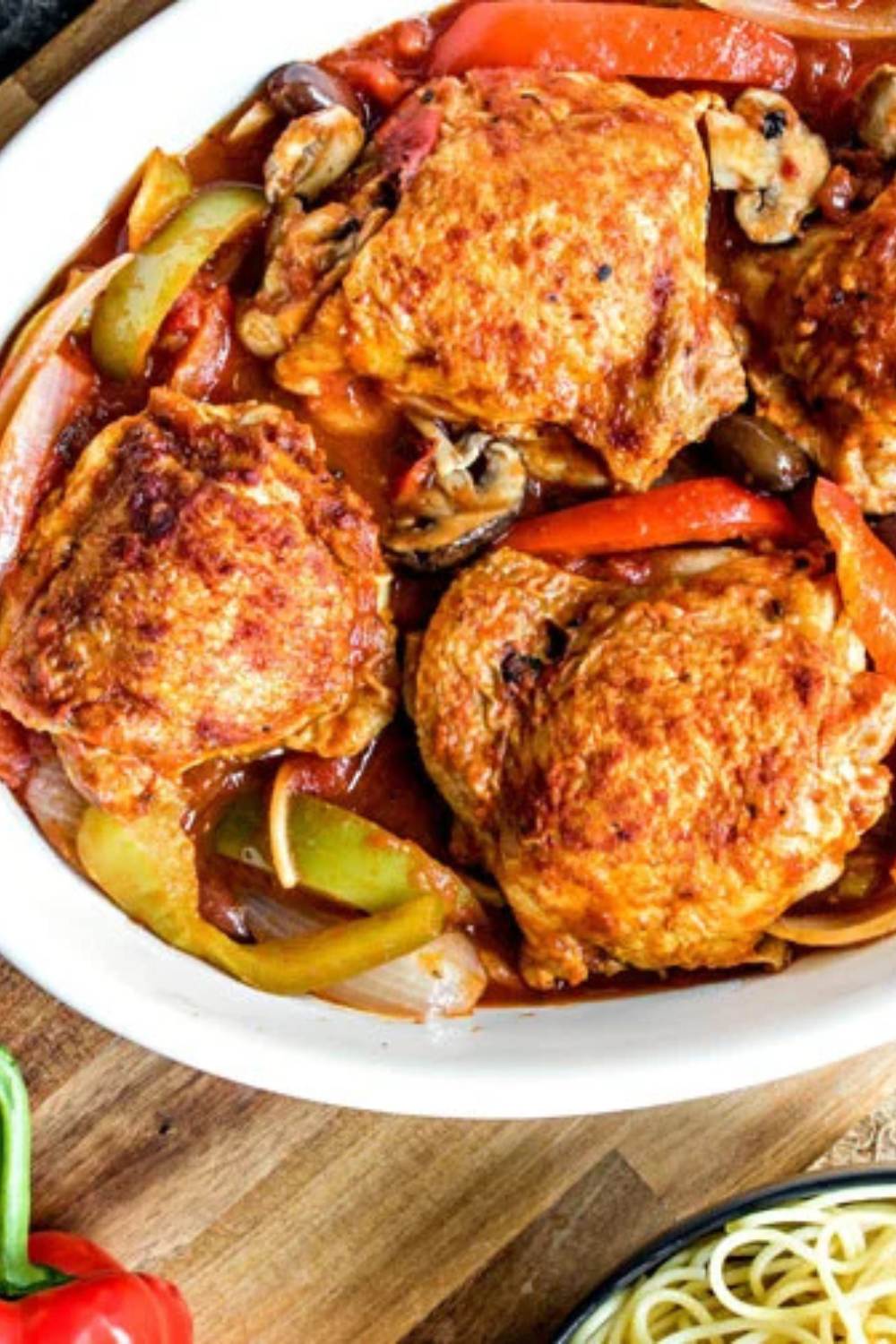 Italian slow cooker recipe: Chicken cacciatore with bell peppers, mushrooms and onions in a white dish.