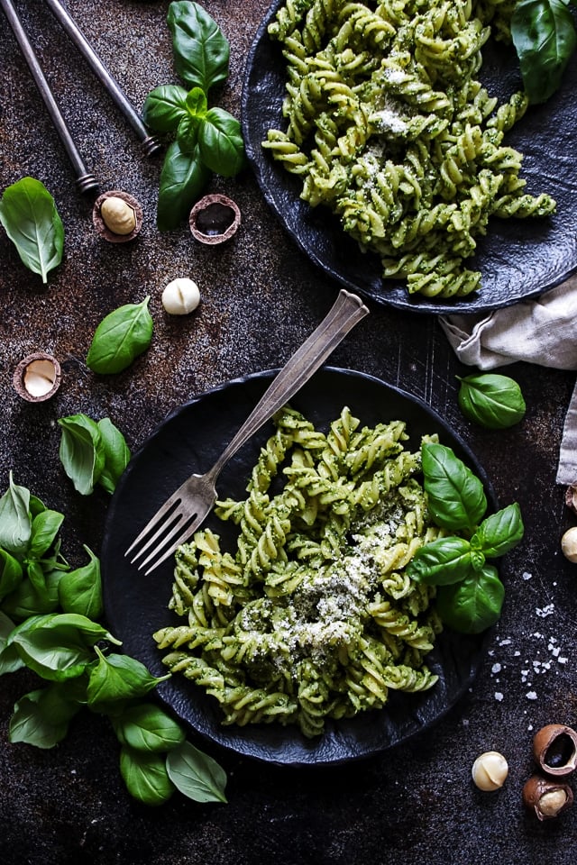 Two plates of vegan Italian pasta with pesto, garnished with fresh basil and vegan parmesan. Part of a collection of easy and delicious vegan Italian recipes.