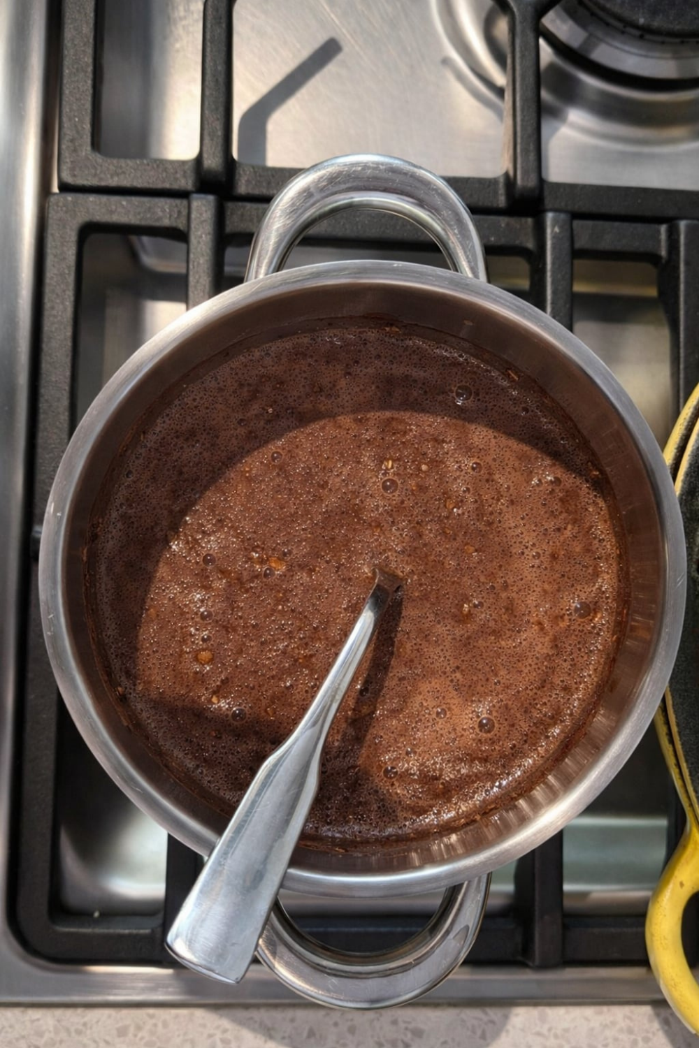 A pot of chocolate oatmeal simmers on a stovetop, ready in 10 minutes. A spoon rests inside the rich, dark breakfast, promising a healthy and delicious one-pot meal.