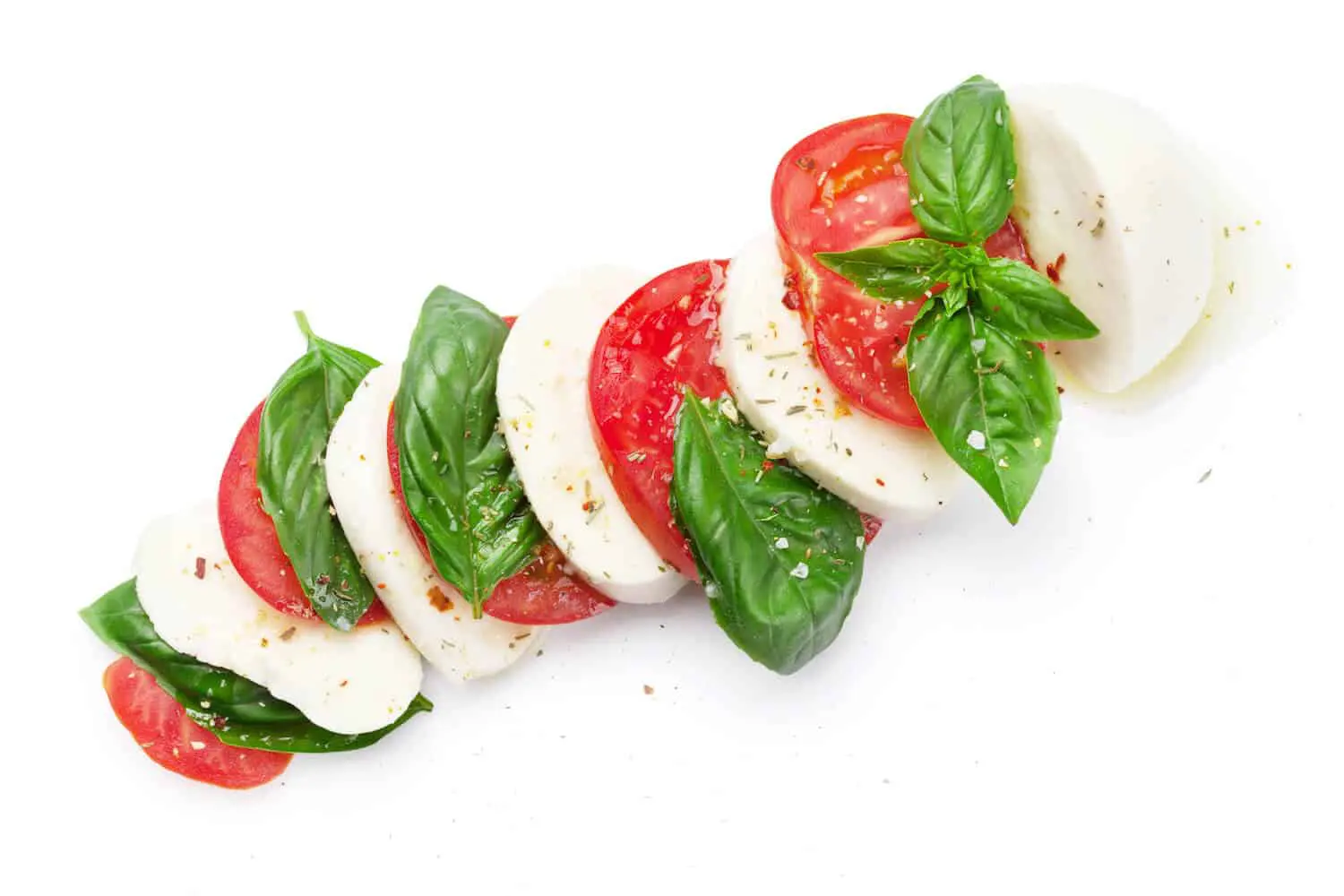 Caprese salad with fresh mozzarella, ripe tomatoes, and basil leaves, seasoned with herbs, a delicious Italian gluten-free recipe.