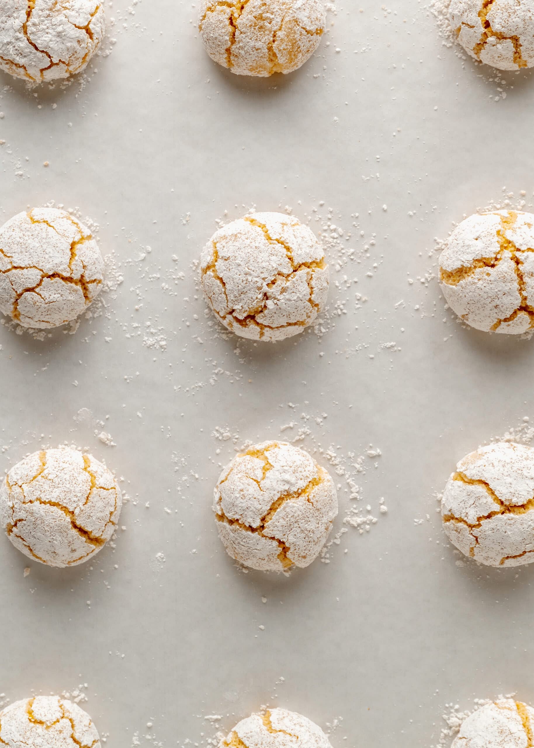 Close-up of Italian gluten-free lemon crinkle cookies dusted with powdered sugar on a white parchment paper background.